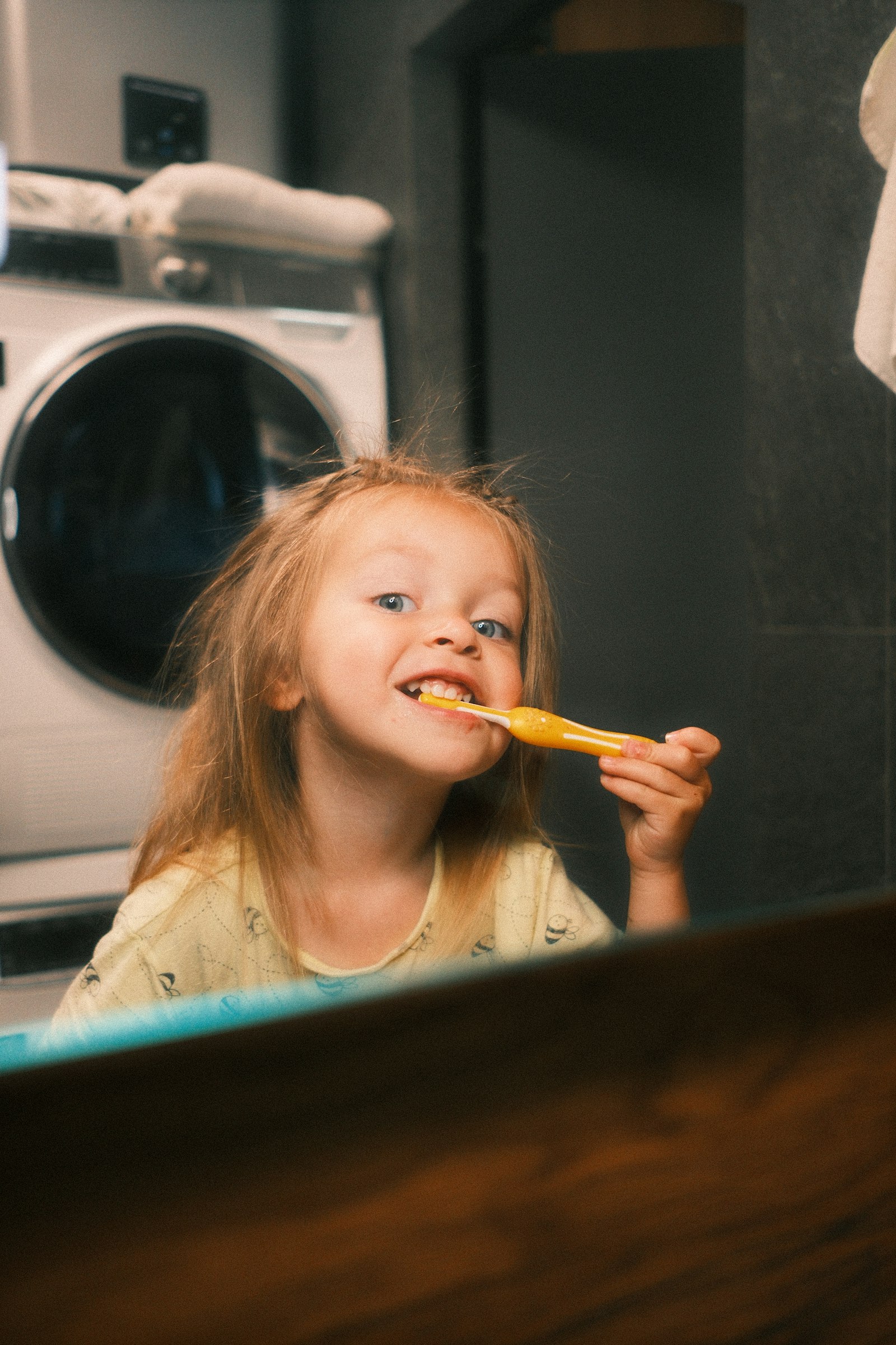 Young girl brushing her teeth at the bathroom mirror