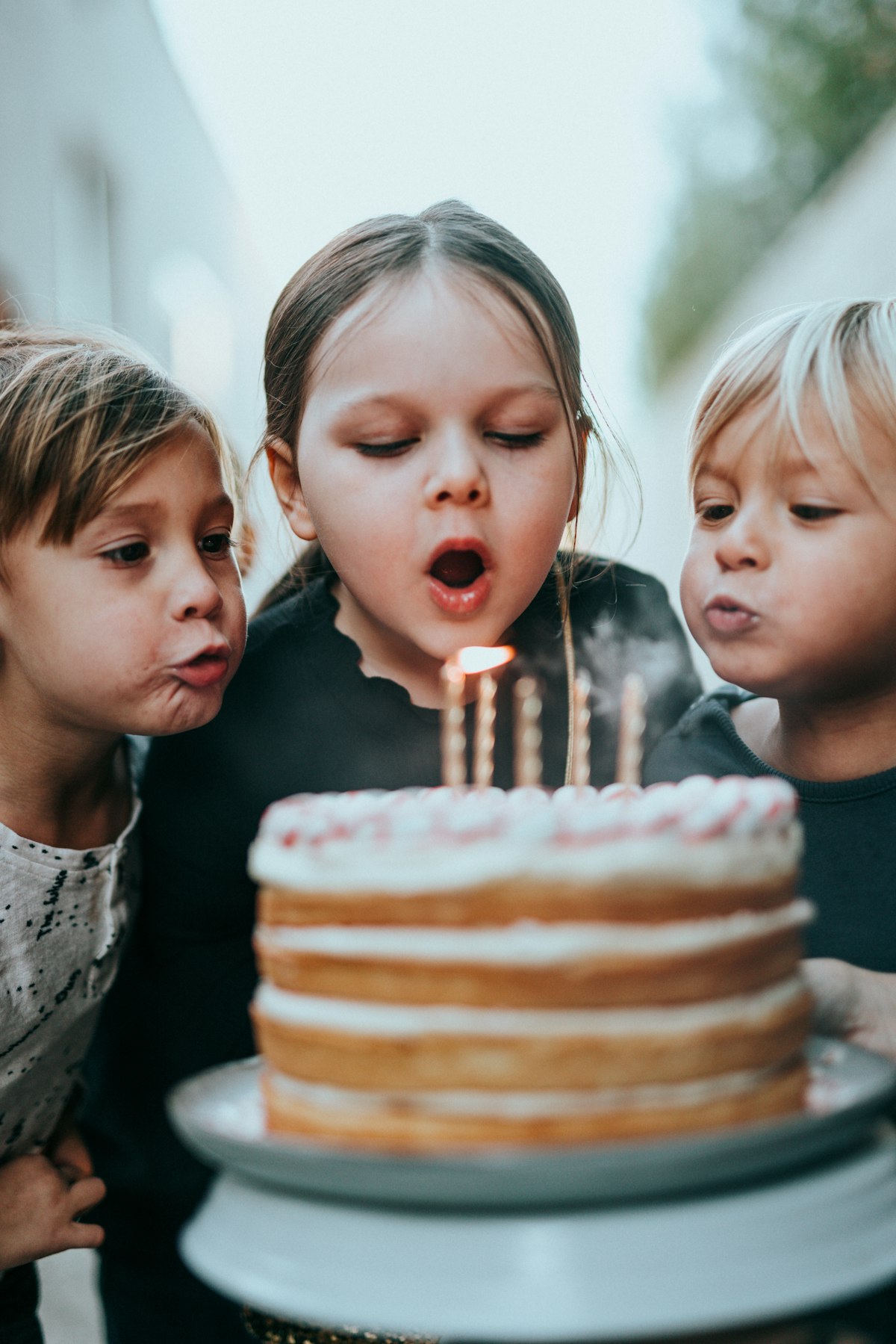 Young children blowing out candles on a birthday cake