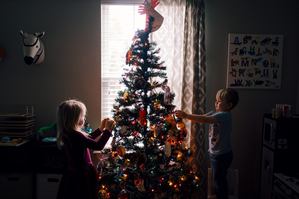 Two young children decorating a Christmas tree together