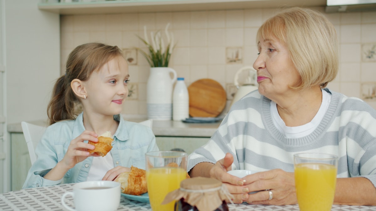 Grandmother and granddaughter sharing breakfast at the kitchen table