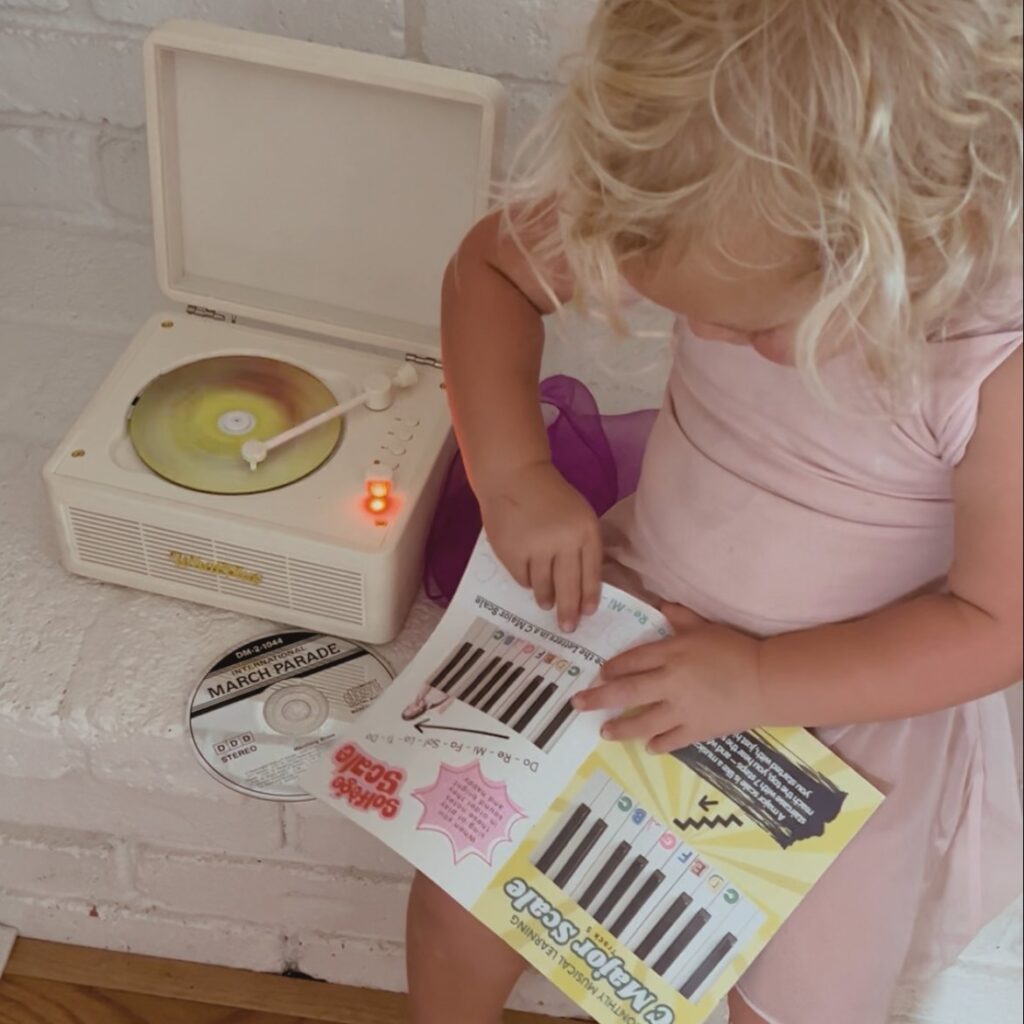 Toddler following the Mailbox Melodies music booklet while a record plays