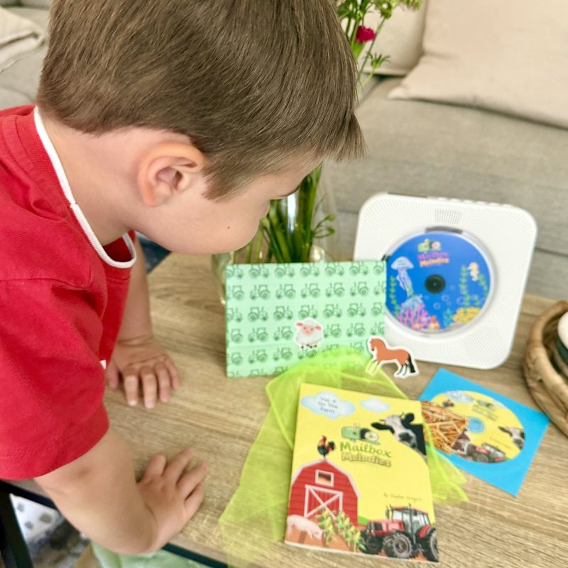 Young child enjoying a Mailbox Melodies envelope, booklet and CD at home