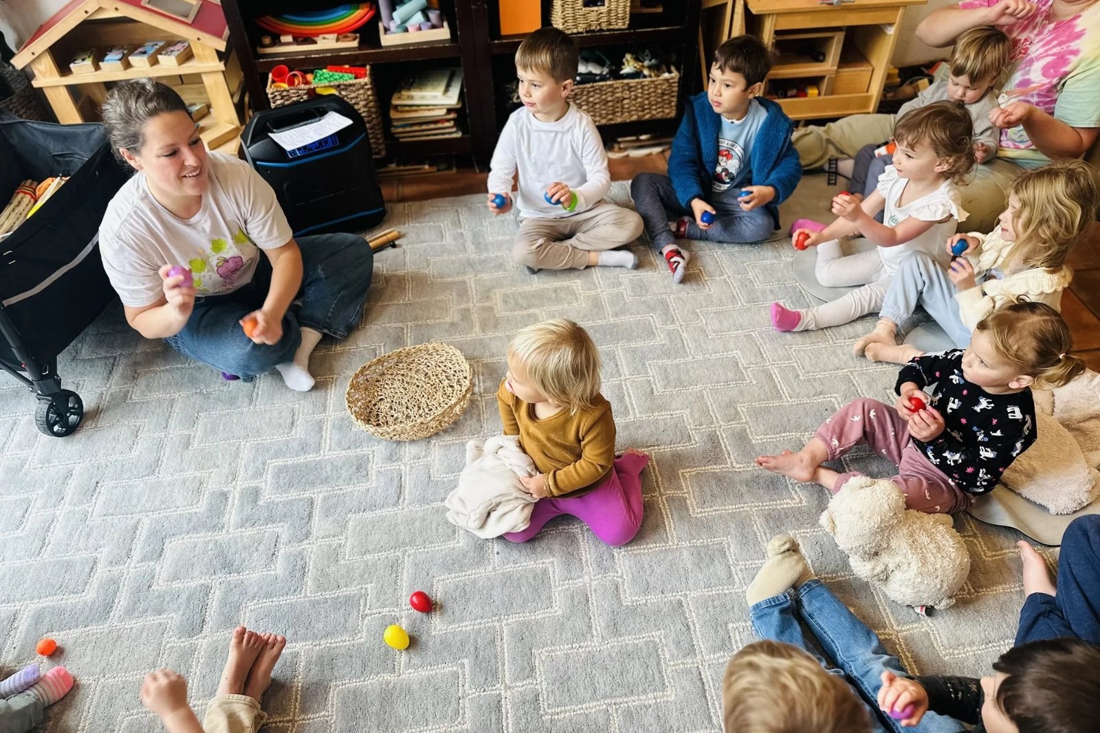 Chelsea leading a toddler music class on the floor with instruments