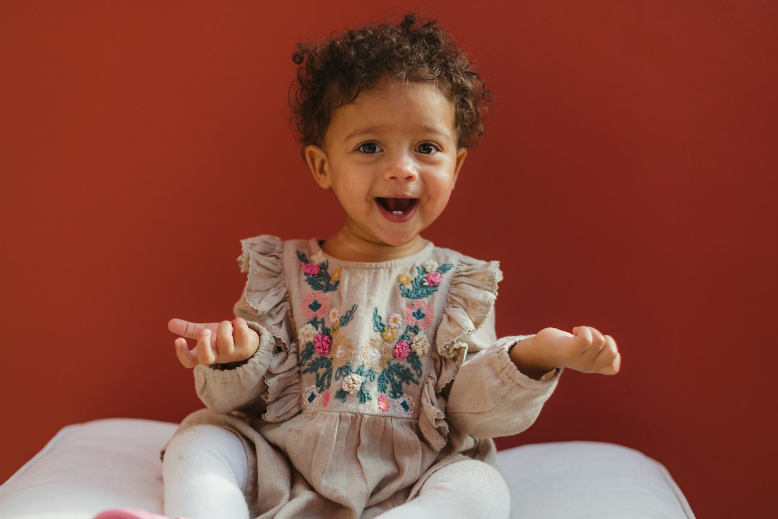 A laughing toddler sitting up and clapping