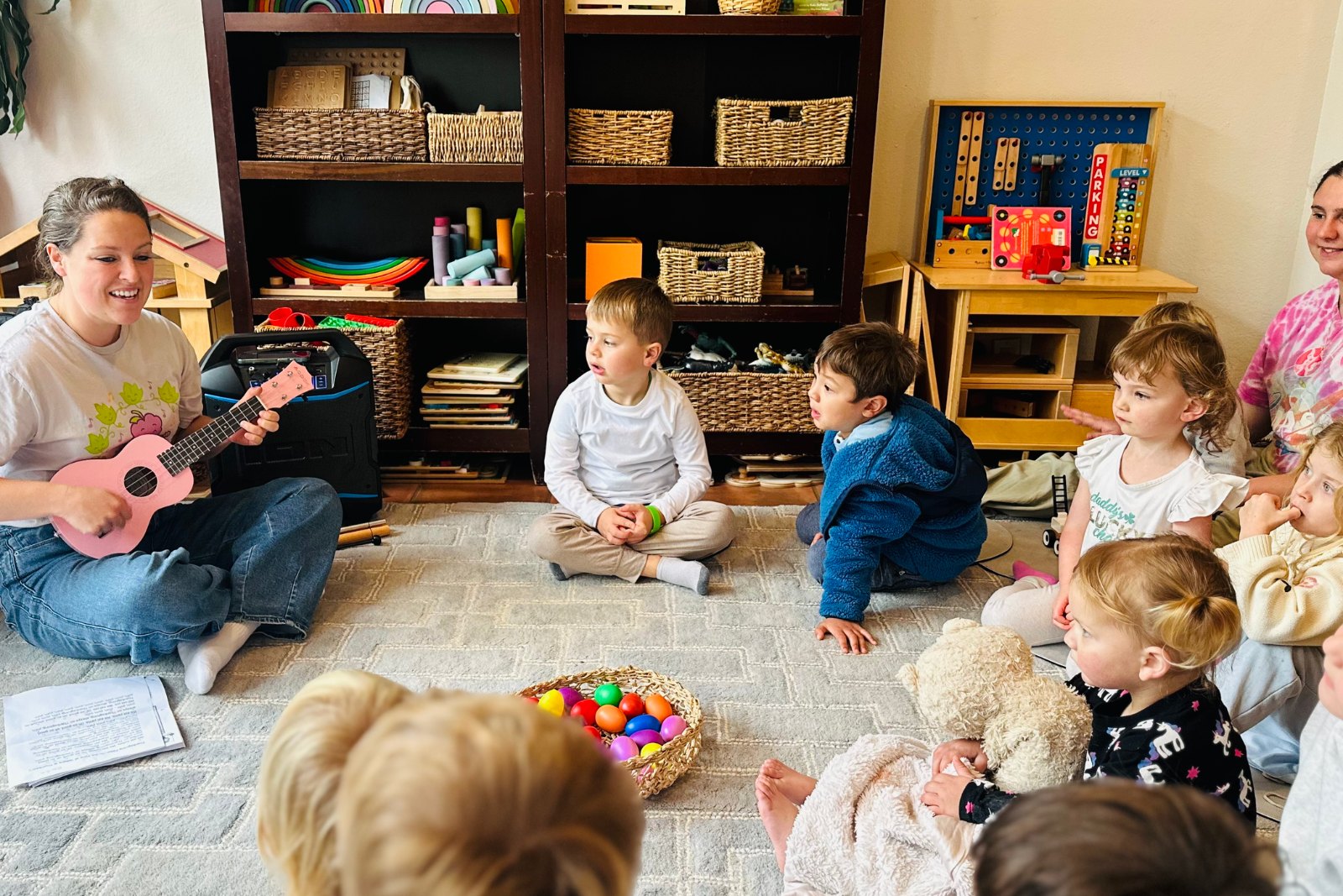 Chelsea playing ukulele for a group of toddlers in class