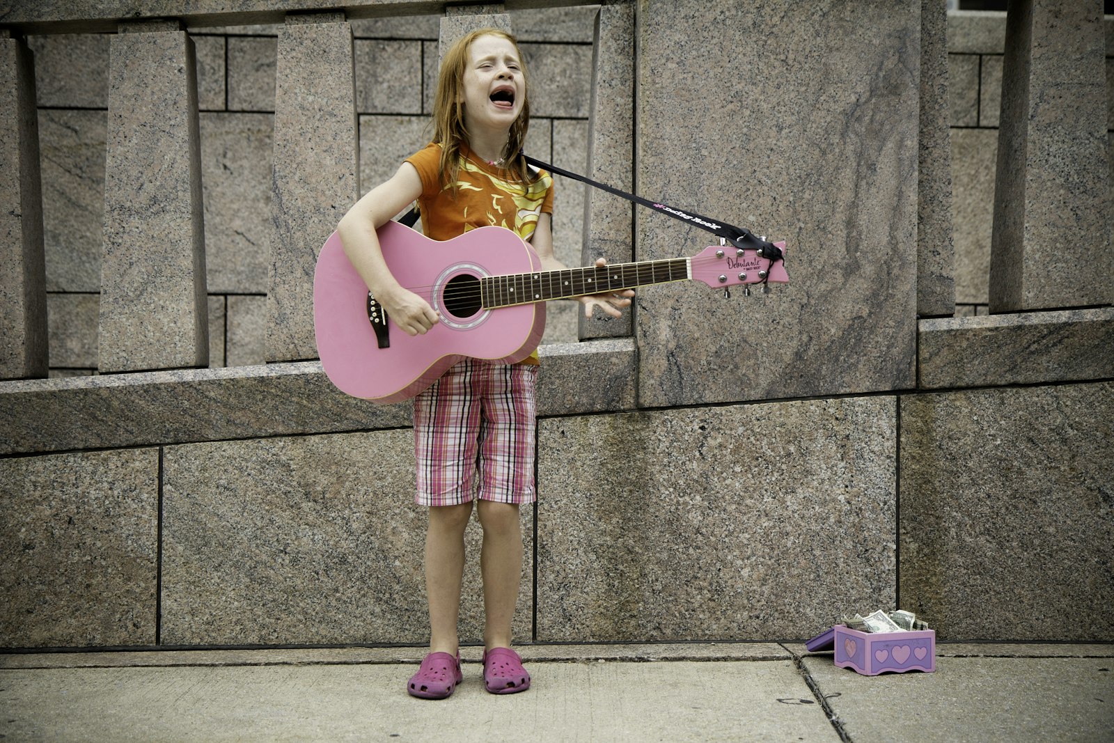 A preschooler strumming a toy guitar and singing