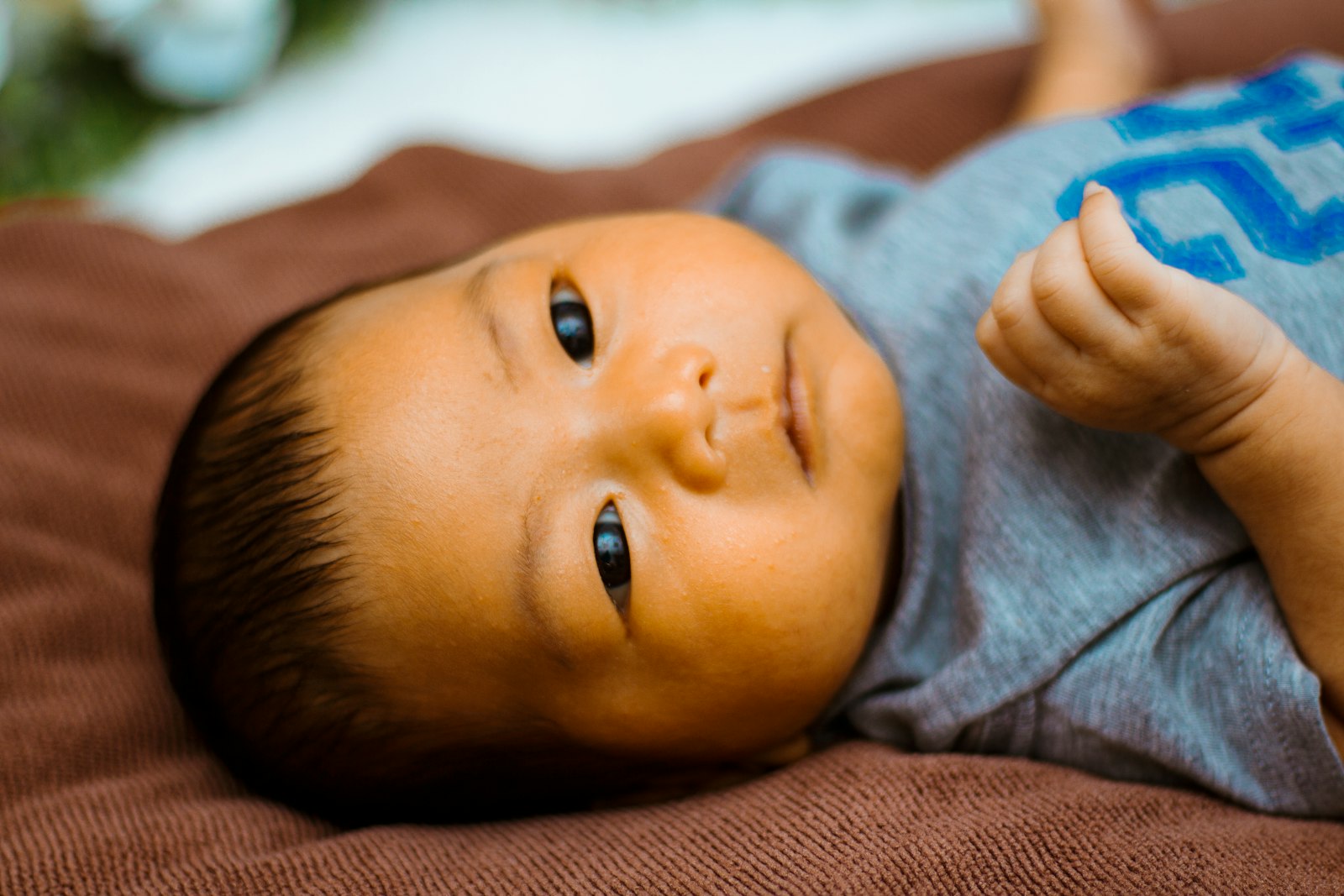 A baby lying on a blanket looking up and listening