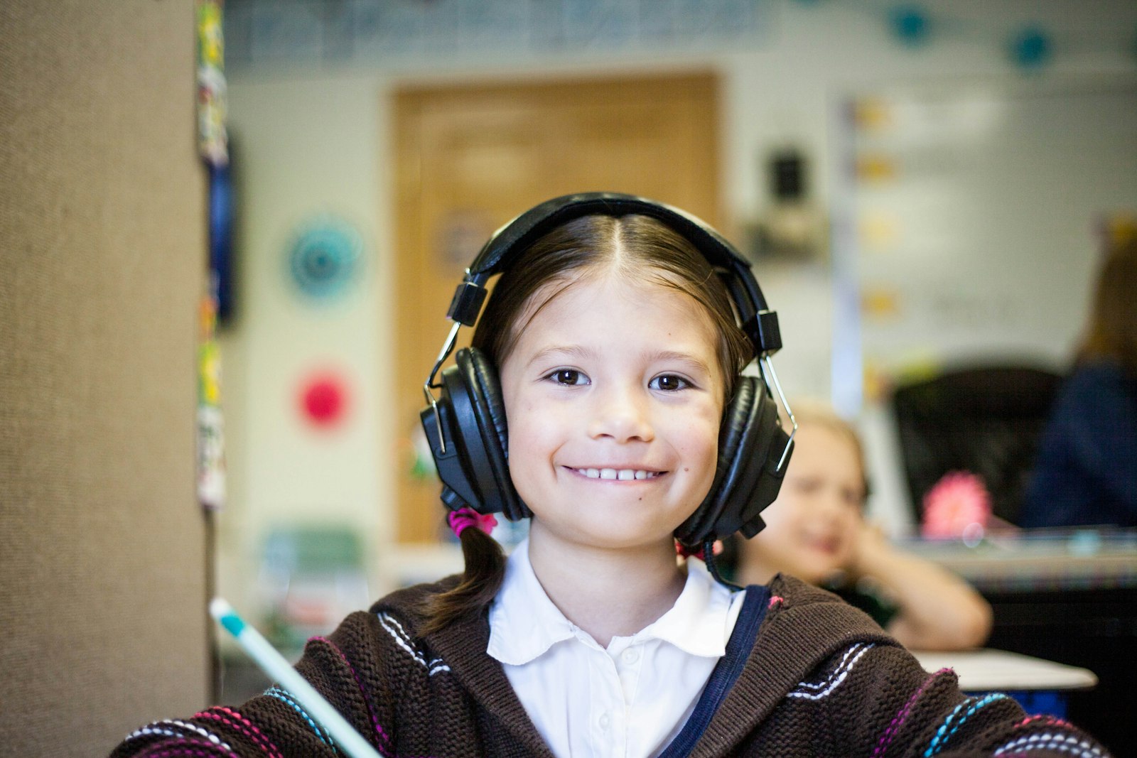 A grinning school-age girl wearing headphones