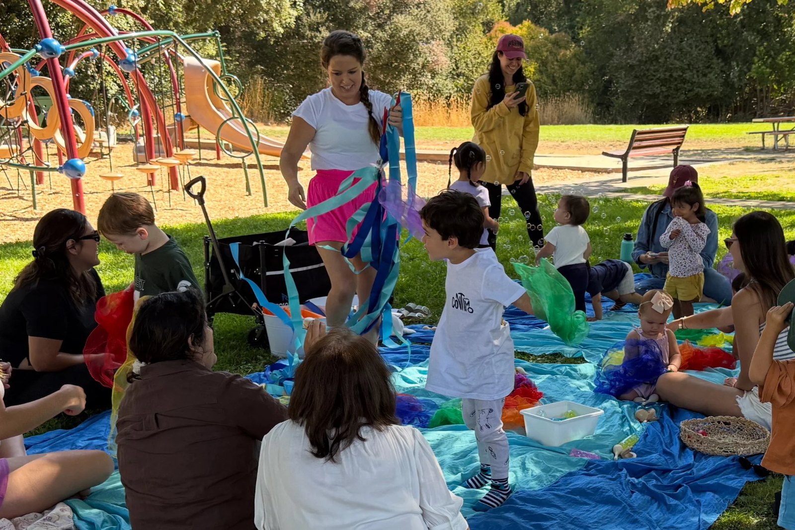 Families gathered on a blanket for an outdoor music class