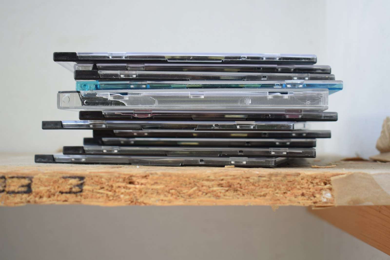 A stack of CD cases on a wooden shelf, a child's own music library