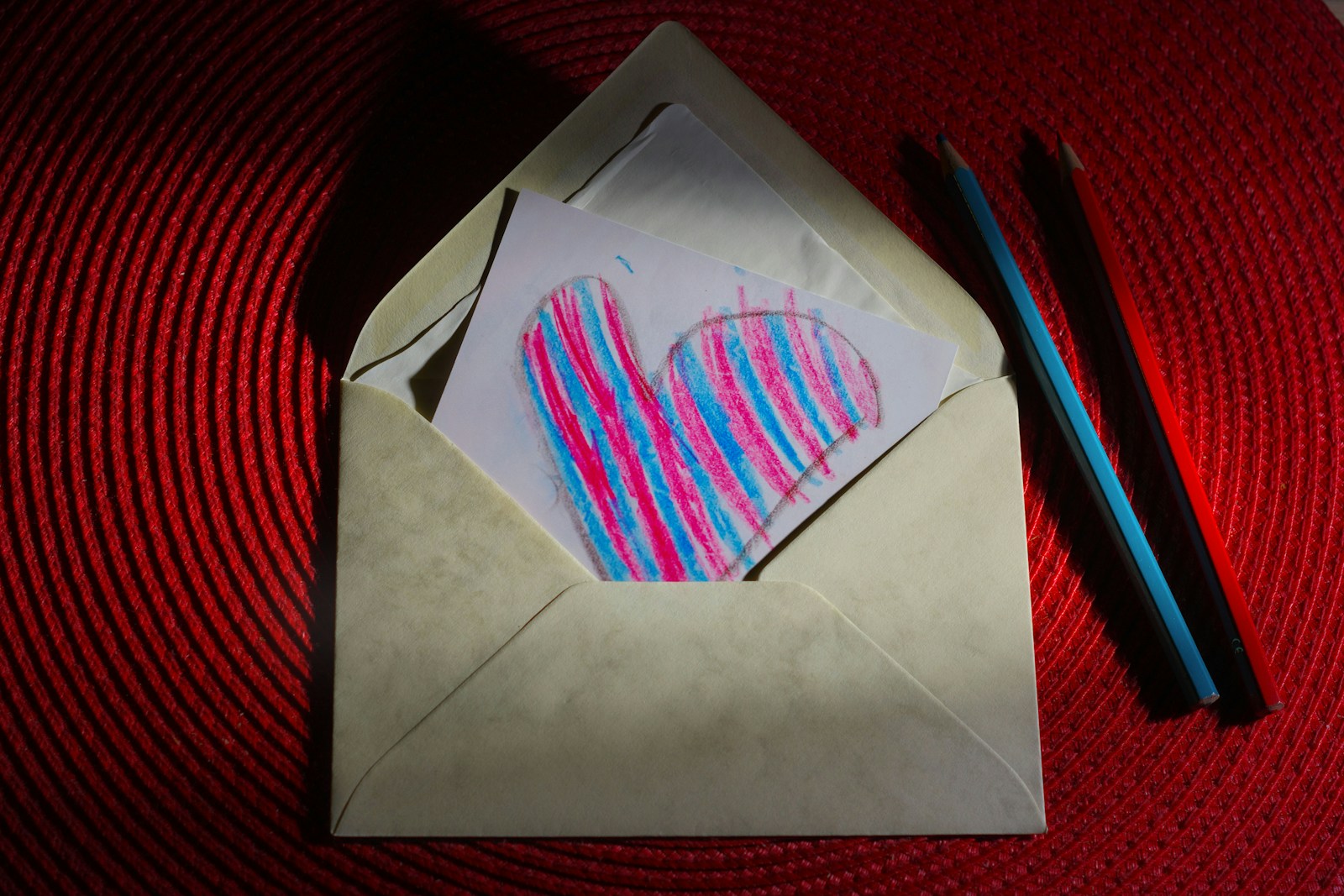 An open envelope holding a child's heart drawing, the kind of mail a kids mail club sends