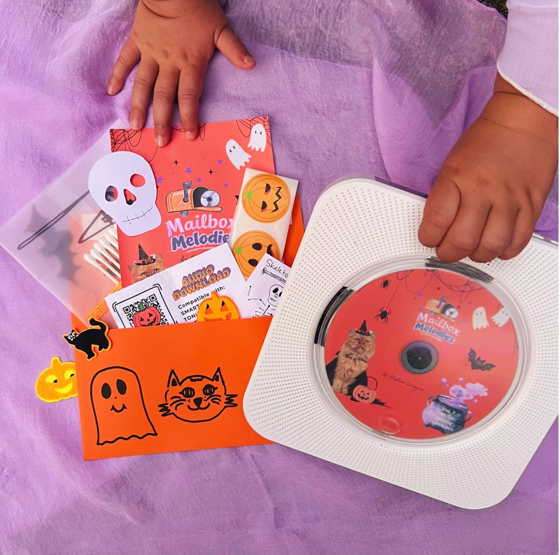 A little one holding the Halloween Mailbox Melodies envelope and the free CD player with the Halloween CD
