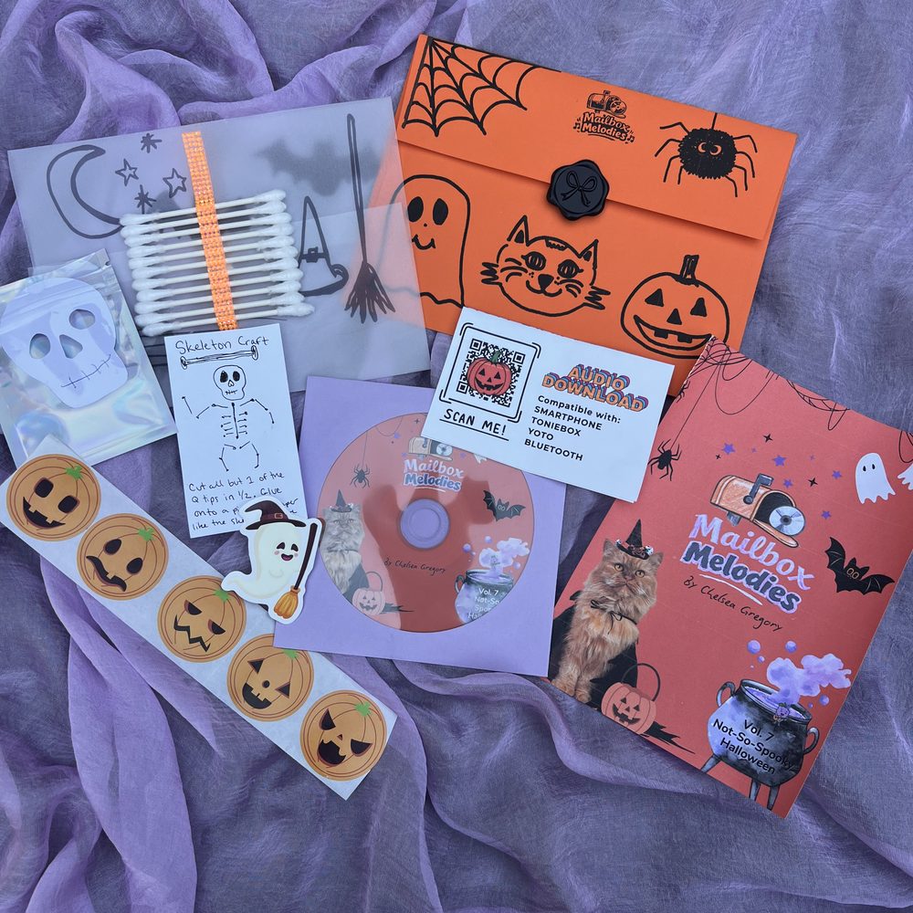 Everything inside the Halloween Mailbox Melodies envelope laid out on purple fabric