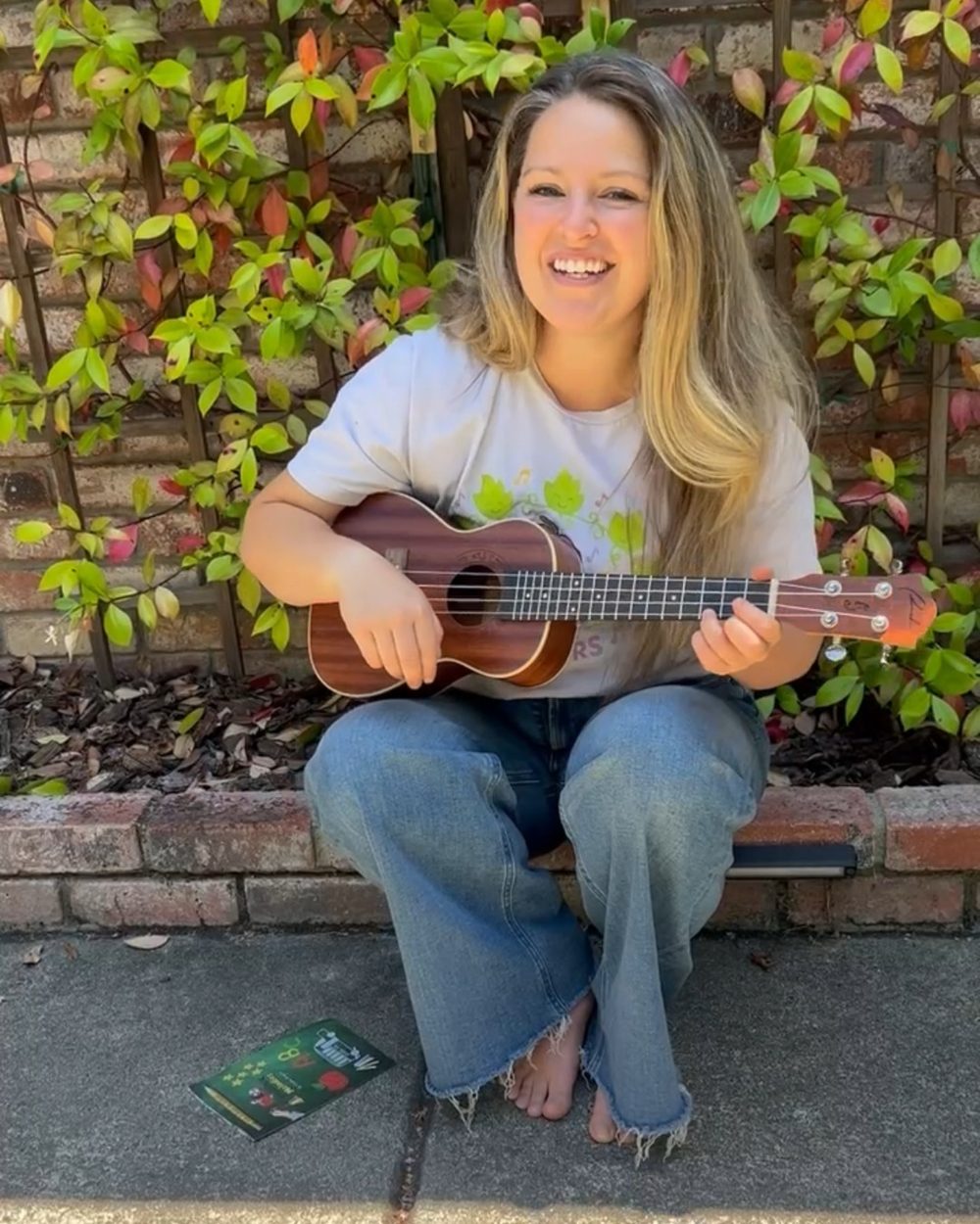 Ms. Chelsea smiling and playing her ukulele