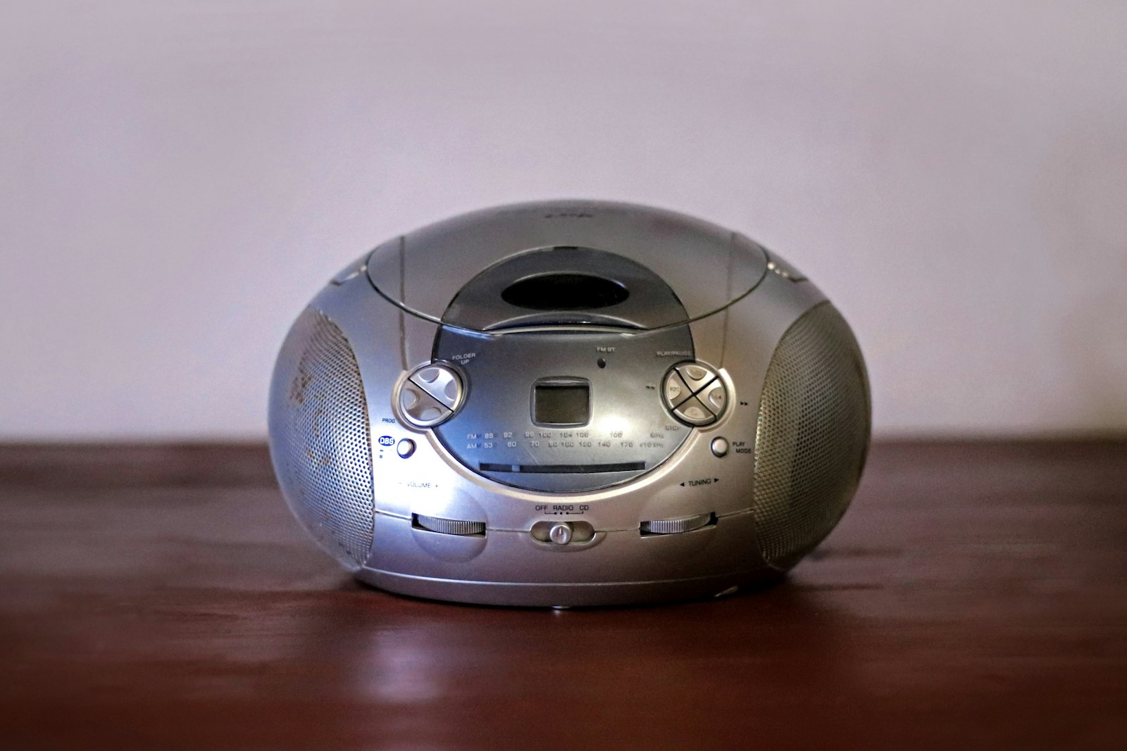A silver CD boombox on a wooden table, a simple music player for toddlers